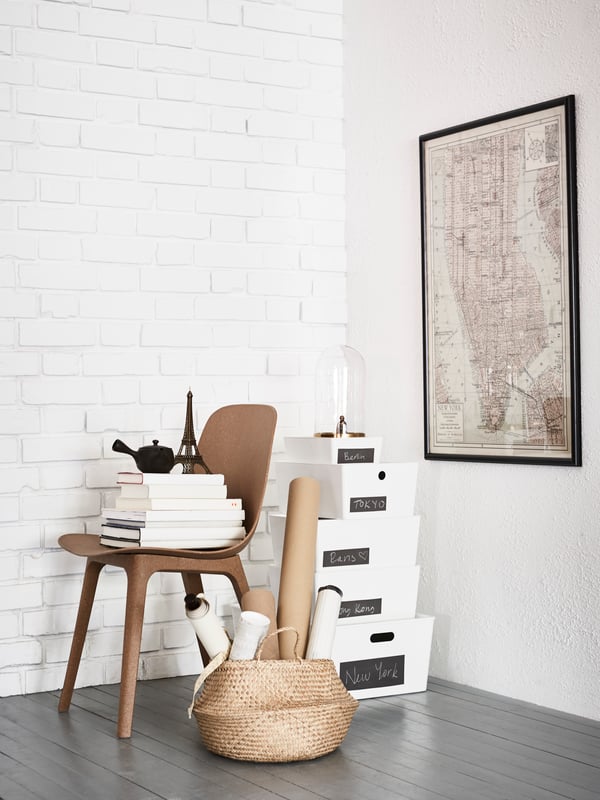 White IKEA KUGGIS storage boxes with lids stacked on a grey wood floor.