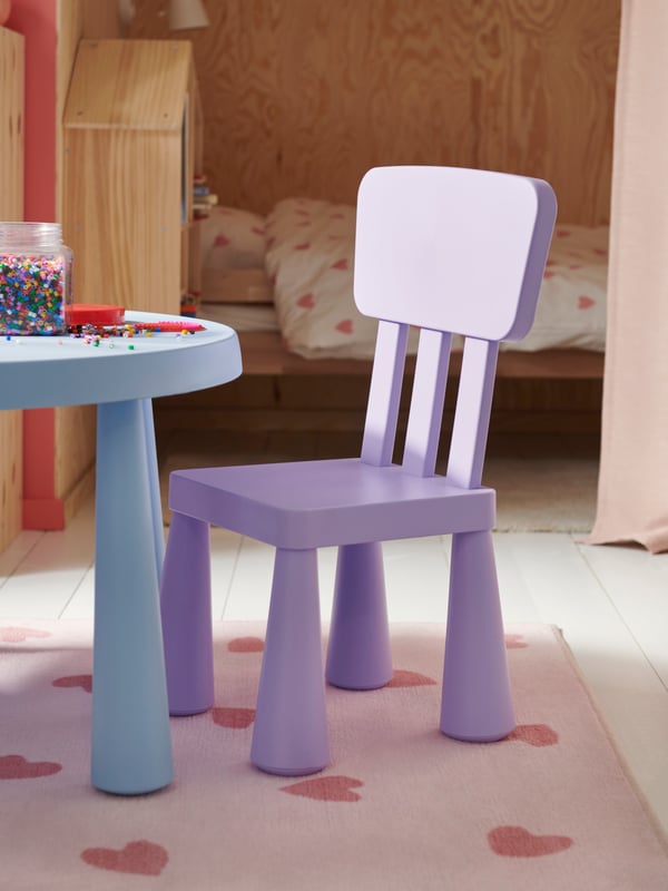Un dormitorio infantil con una alfombra BARNDRÖM y sobre ella una mesa y silla MAMMUT.