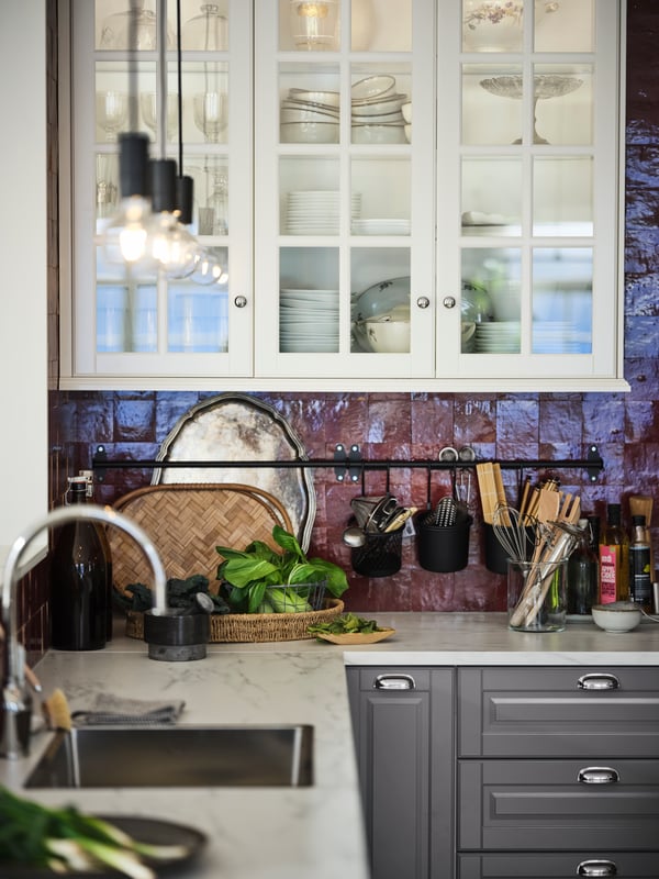 An EKBACKEN white-marble-effect worktop with METOD cabinets and MAXIMERA interiors in a red-tiled kitchen.