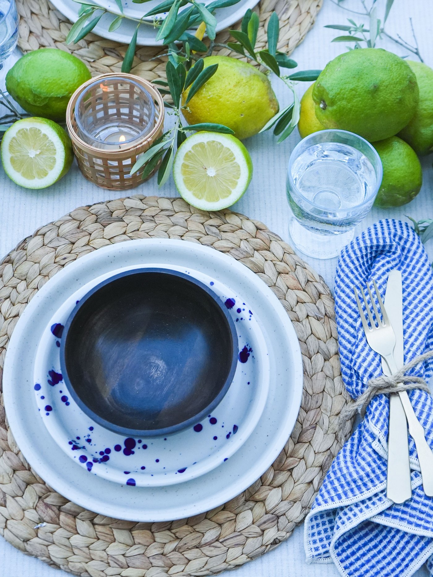 Sommerlicher Esstisch mit frischen Zitronen, Olivenzweigen, blau-weissem SILVERSIDA Geschirr und rustikalem Besteck.
