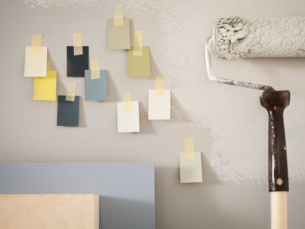 Image of colour swatches taped to a wall, next to a paint roller