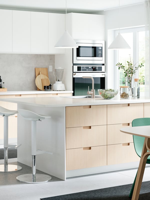 A kitchen island with white cabinets on the wall.