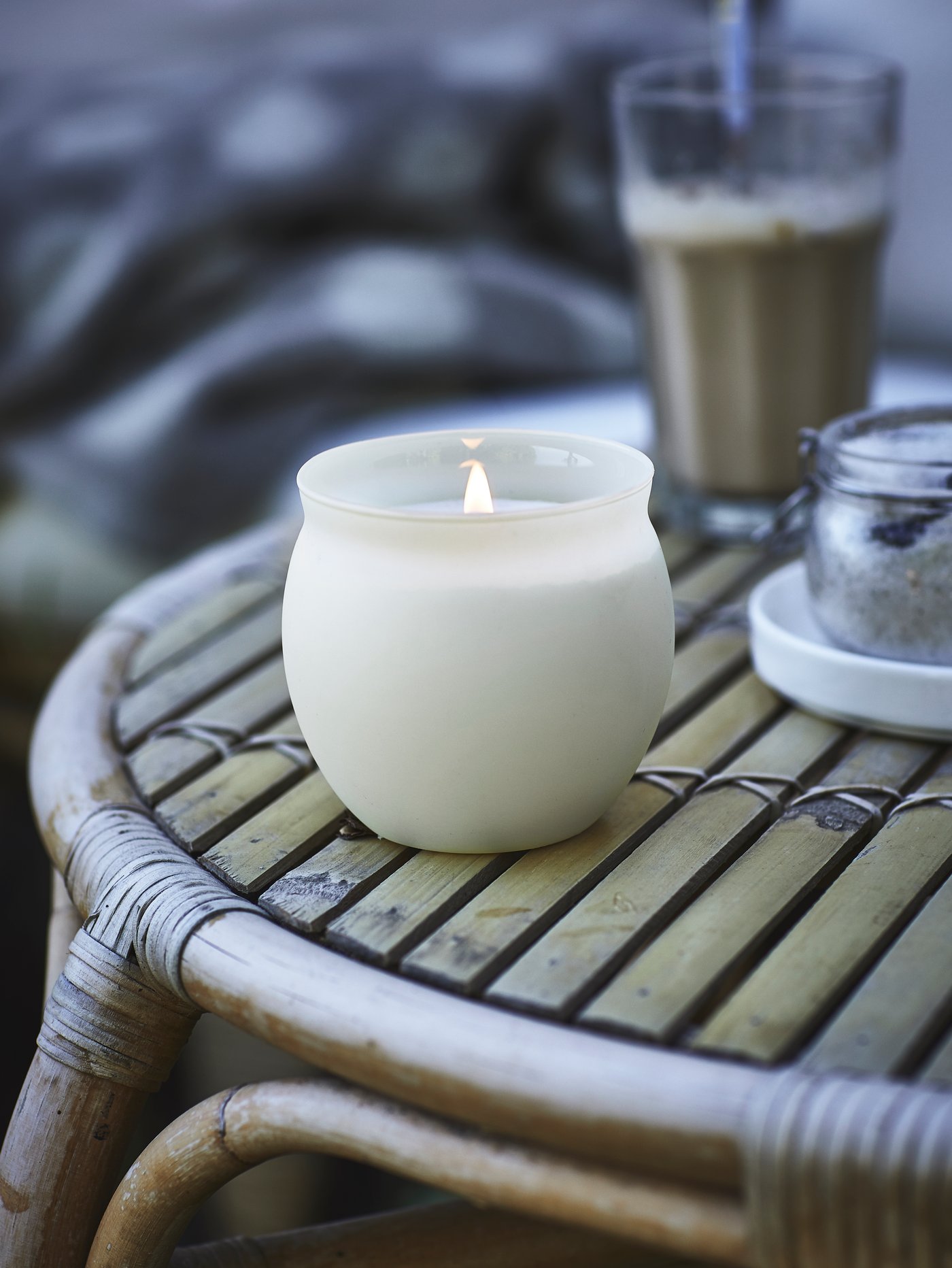 Vela de vainilla en un vaso de vidrio encendida sobre una mesa de madera