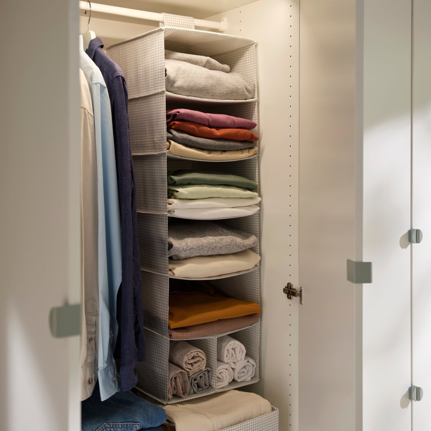 STUK hanging organiser in white with several shelves holding folded clothes and towels inside a wardrobe.