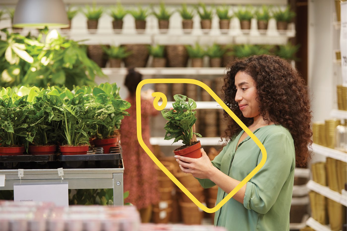 En kvinde står i et IKEA varehus med en plante i hånden