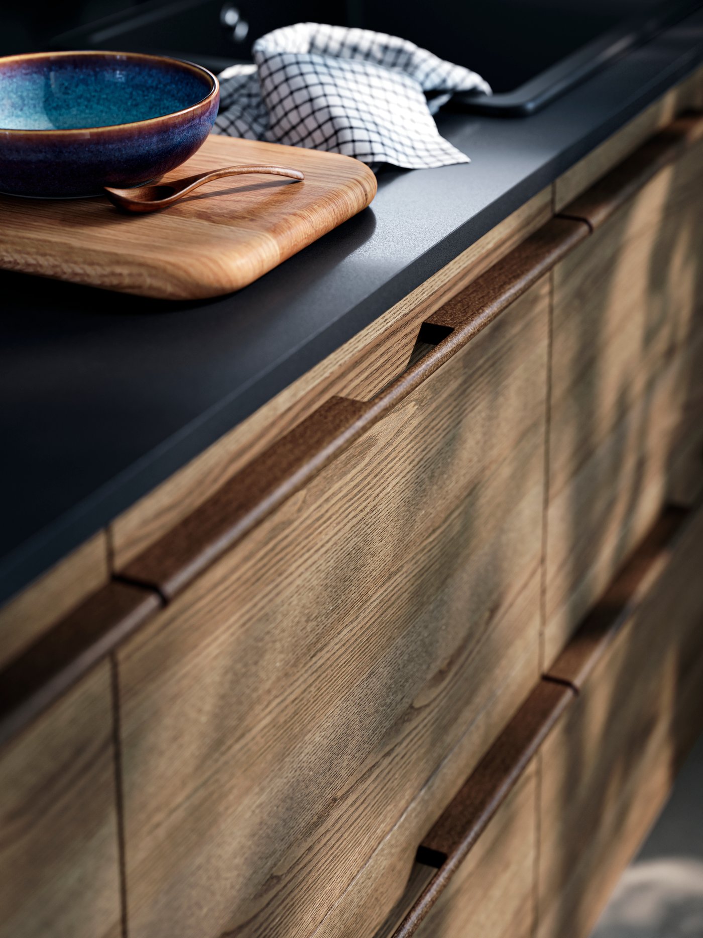 STENSTA dark brown ash veneer drawer fronts, a sleek black countertop, with a wooden cutting board and ceramic bowl on top.