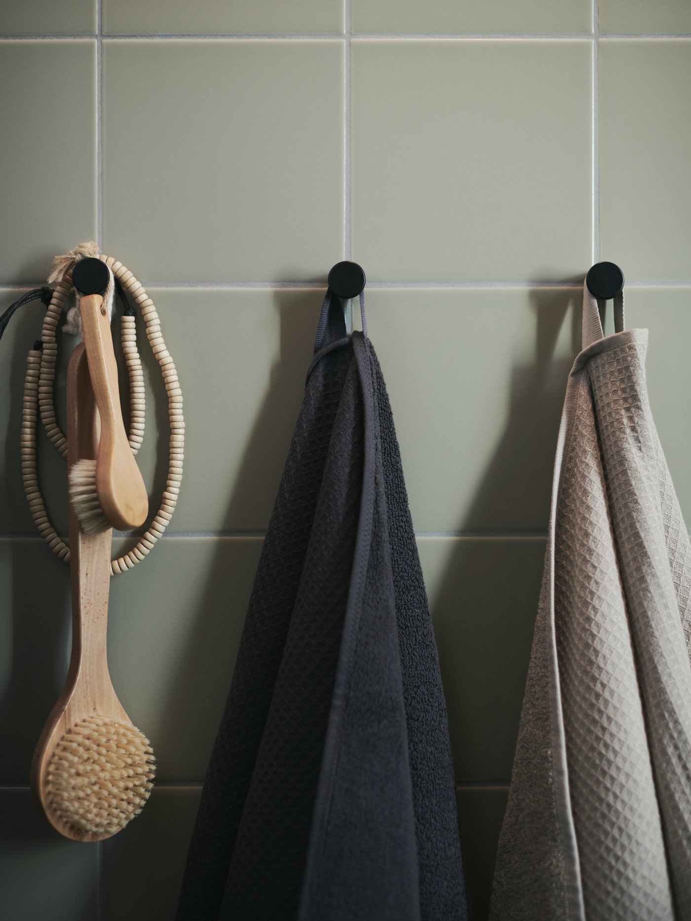 SALVIKEN towels in anthracite and dark beige hang from hooks.