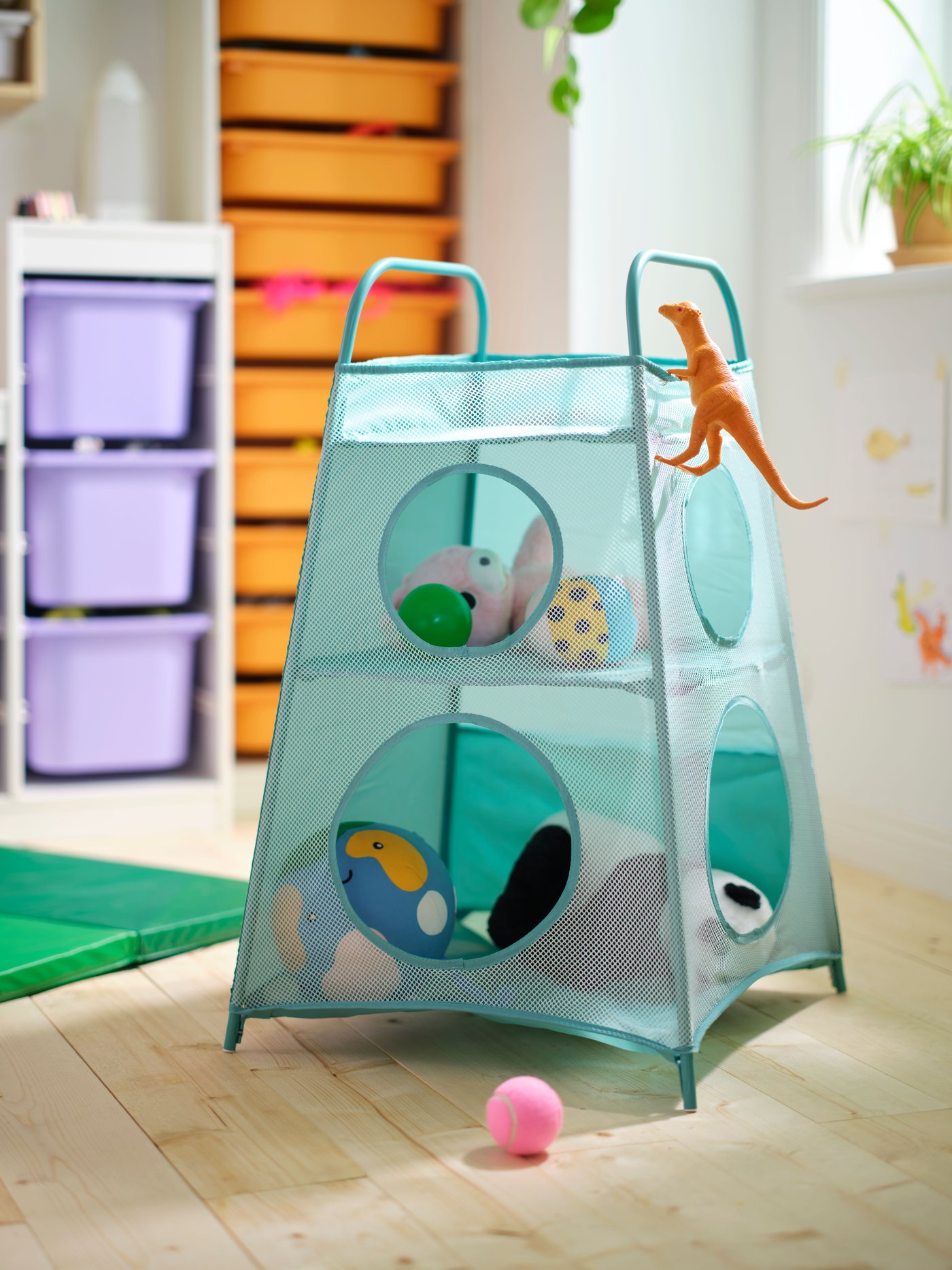 A turquoise TIGERFINK storage with compartments is placed on the floor in a room. There are toys in, on, and around it.