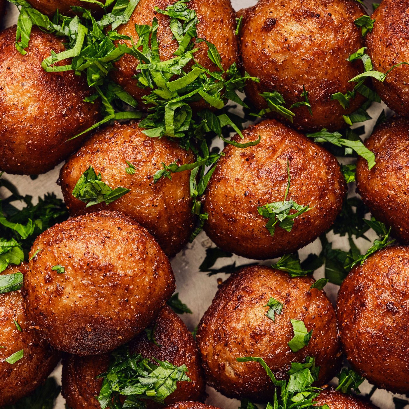 Several HUVUDROLL plant balls, fried golden-brown, are garnished with fresh green herbs and ready to serve.