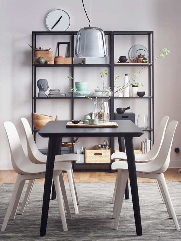 A LISABO table set for a meal for four people, surrounded by ODGER chairs and an EVEDAL pendant lamp.