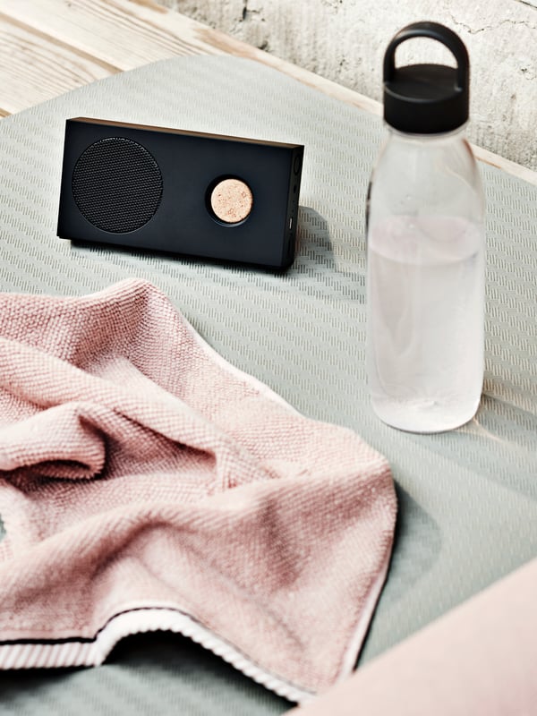 IKEA 365+ boca za vodu pored ENEBY prenosivog Bluetooth zvučnika i svetlorozeg VIKFJÄRD peškira za goste.