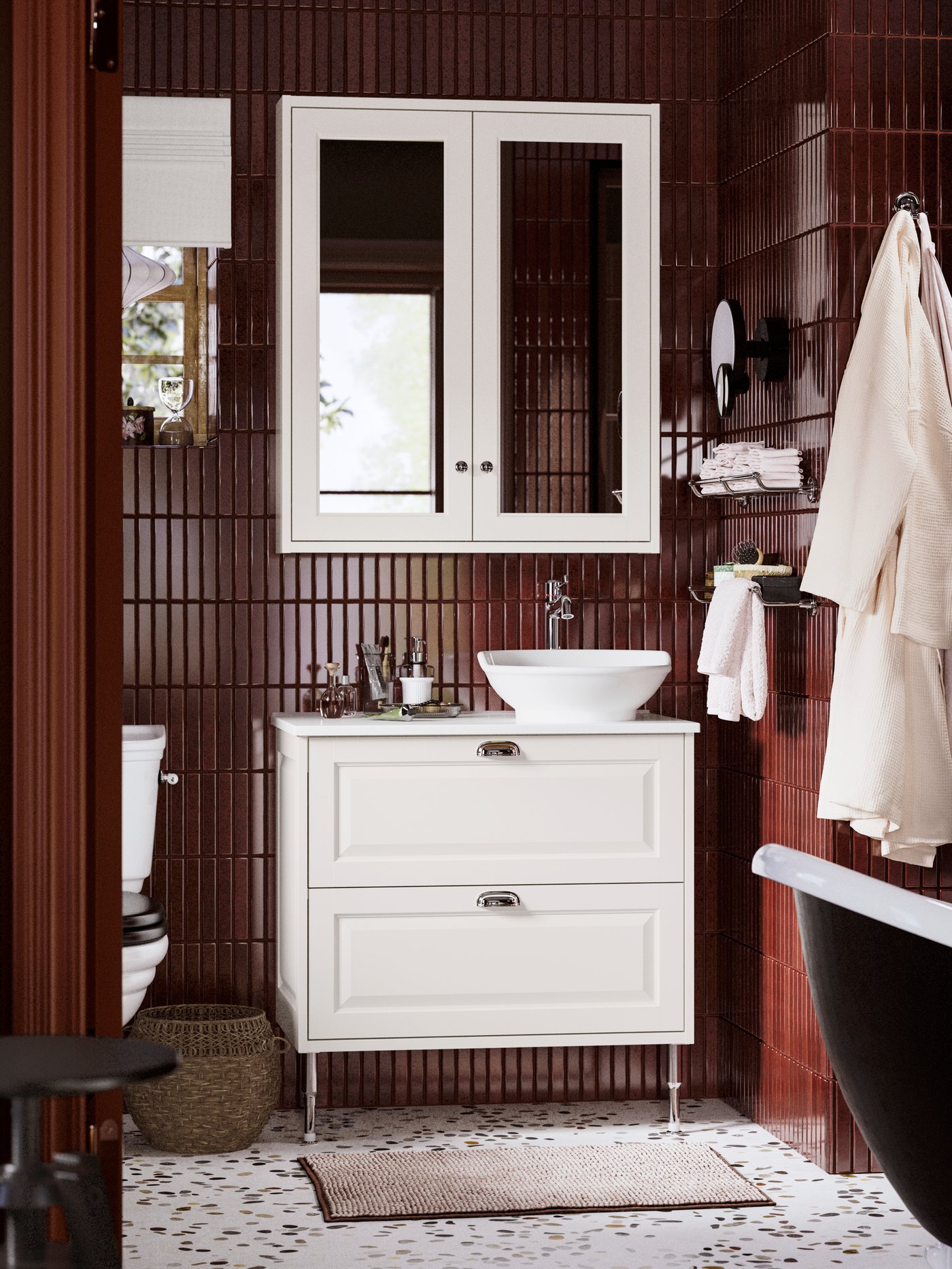 A bathroom featuring a TÄNNFORSEN wash-stand with drawers, a vessel sink, dark maroon tiles, and a mirror cabinet above.