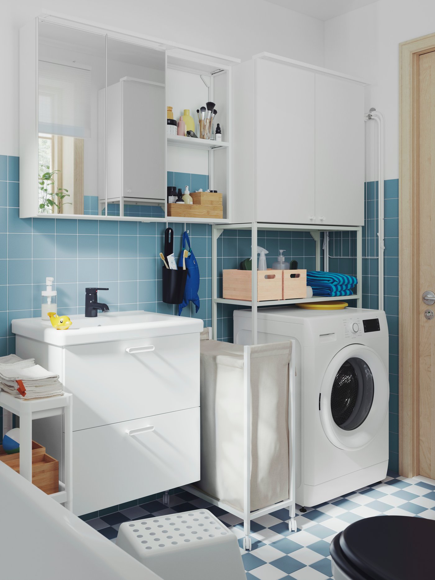 A small, blue-tiled bathroom has a white ENHET wash-stand, a mirror cabinet, a high cabinet and a white VESKEN trolley.