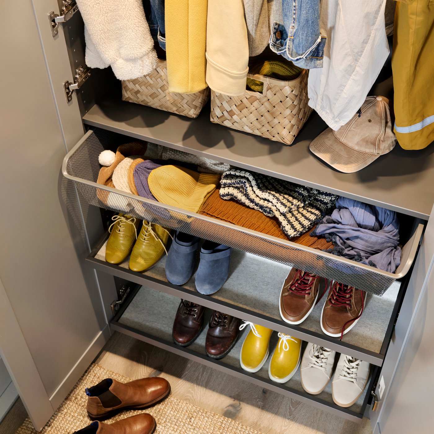 Gros plan du bas d’une armoire-penderie PAX GULLABERG avec une tablette, une corbeille en filet coulissante et des range-chaussures.