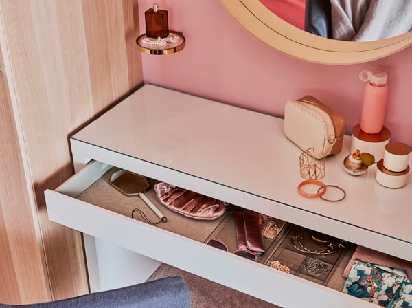 Close-up of a MALM dressing table with an open drawer showing makeup.