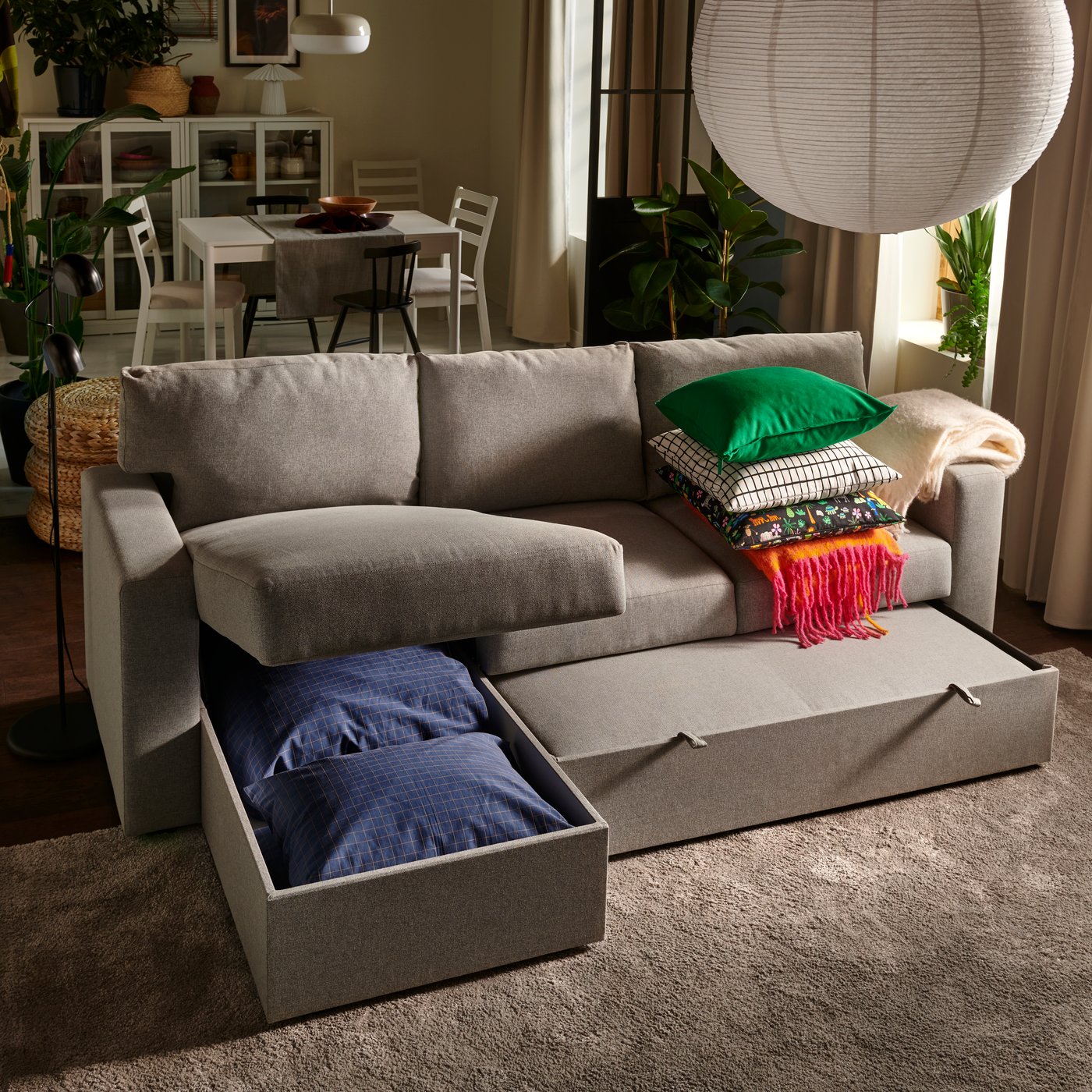 A living room with a beige/grey BÅRSLÖV 3-seat sofa-bed with chaise longue, halfway between sofa and bed mode.