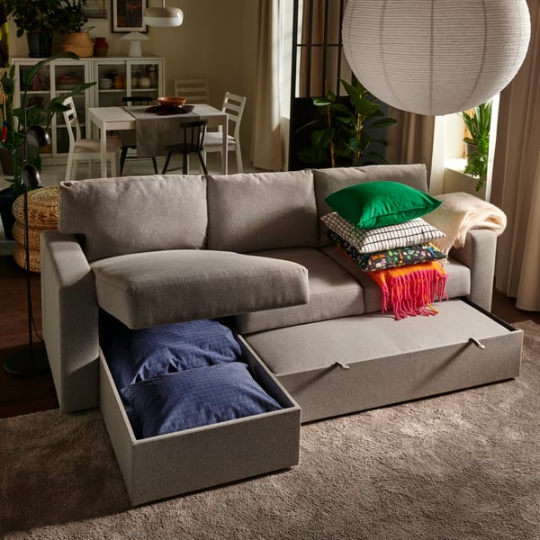 A living room with a beige/grey BÅRSLÖV 3-seat sofa-bed with chaise longue, halfway between sofa and bed mode.