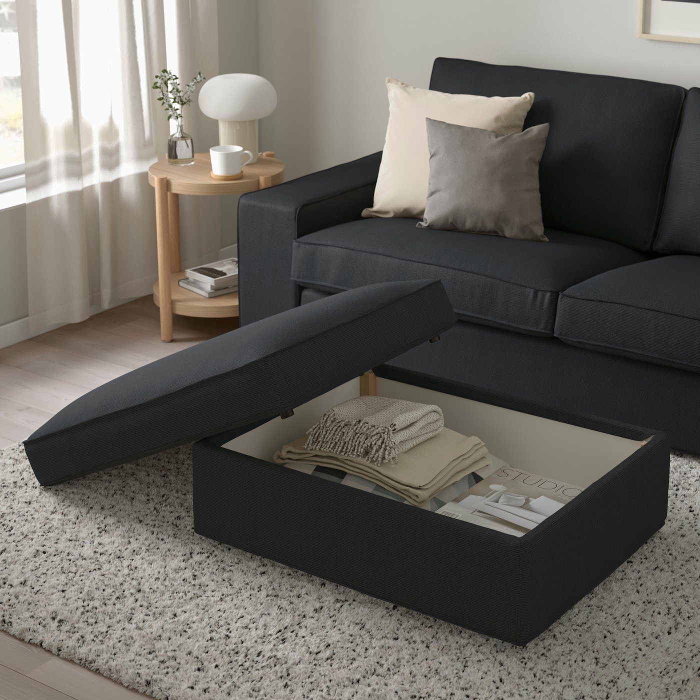 Anthrazitfarbiger KIVIK Fußhocker mit TRESUND Bezug und Stauraum im Wohnzimmer.