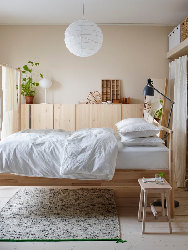 A bright bedroom with a double bed and a solid wood cabinet lining a wall.