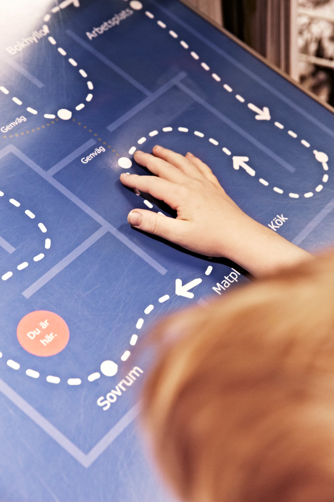 Main d’enfant suivant le pointillé matérialisant le trajet des visiteurs sur le plan d’un magasin IKEA.