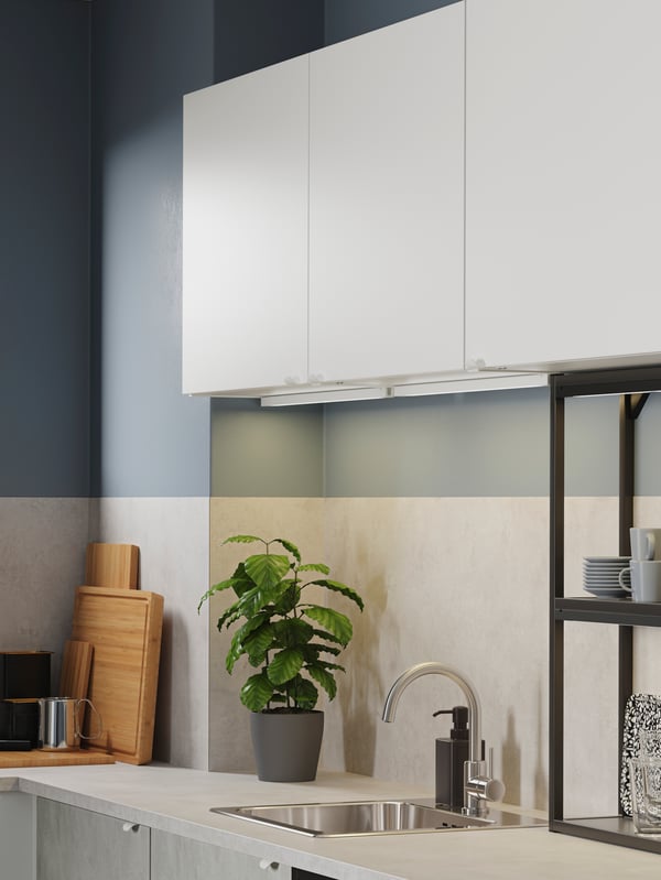 Kitchen with white cabinets, black open shelves, concrete-effect fronts, a mixer tap in zinc and LED lighting strips.