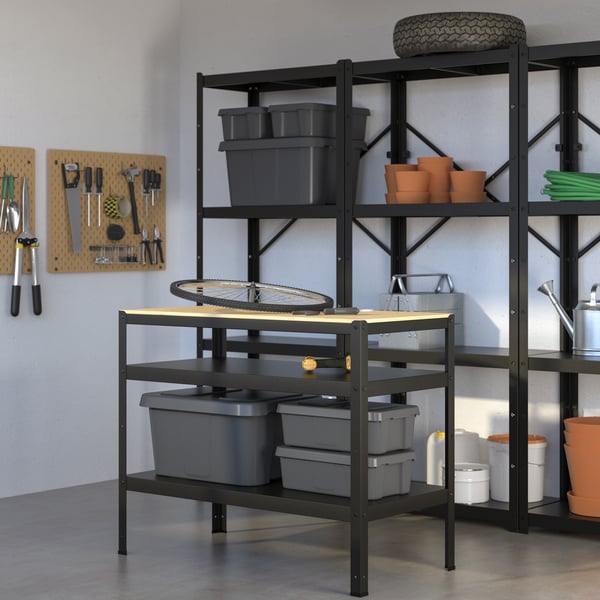 Un taller con un meson akto y un gran estante organizando herramientas, cajas y maceteros