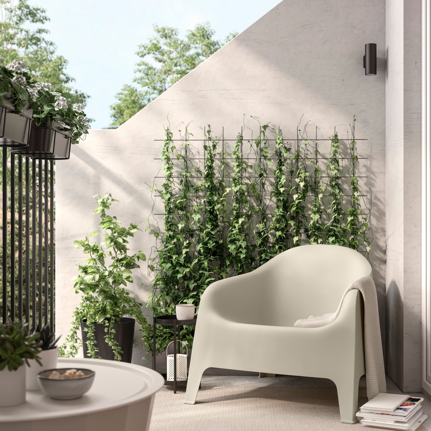A beige SKARPO garden chair in an outdoor setting surrounded by lush greenery, with climbing plants growing on a trellis against the wall.