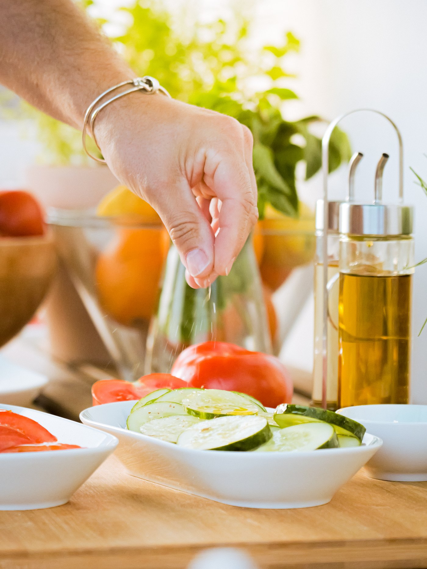 A hand reaches for some vegetables, laid out on an IKEA 365+ serving plate.
