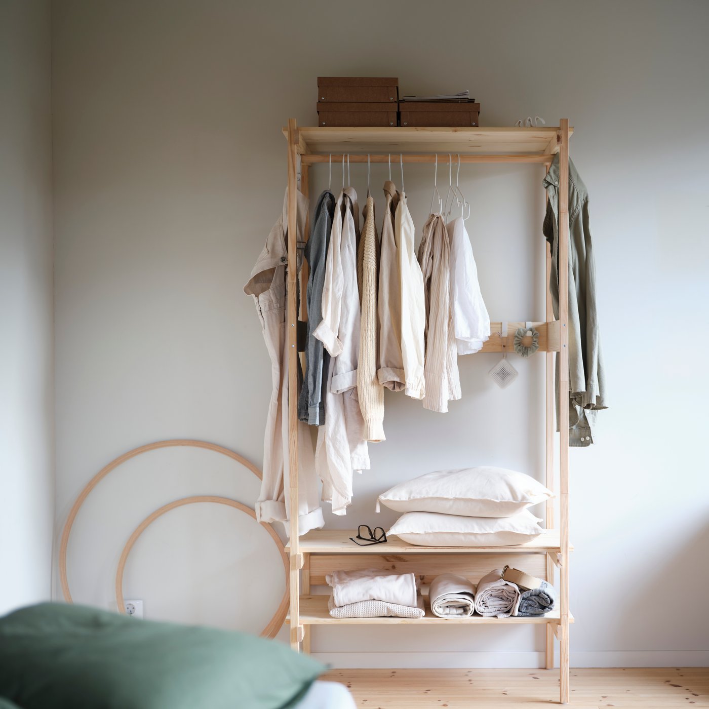 KRONÖREN open wardrobe in pine with hanging clothes and baskets on shelves in a calm, organised bedroom space.