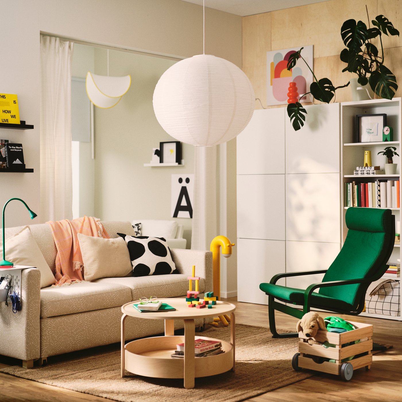 Lámpara de techo GULLSUDARE blanca colgante en una sala de estar, sobre una mesa de centro y junto a un sofá y un sillón verde.