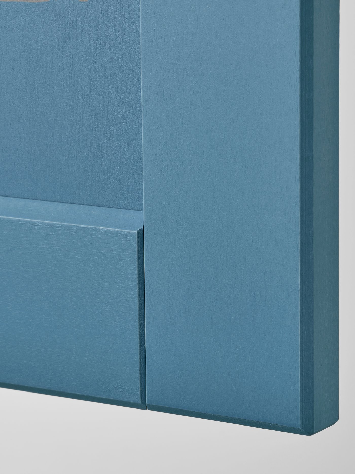 A closeup of a blue LERHYTTAN front, showing the bevelled edge, inset veneer panel and frame of solid wood.