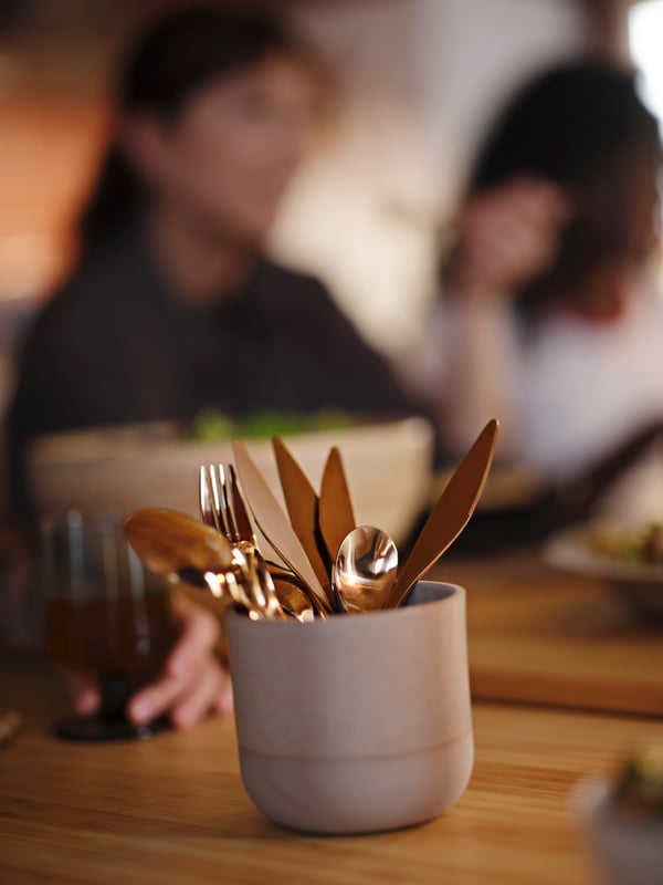 A rose-gold colour FÖRNUFT 24-piece cutlery set in the dining room
