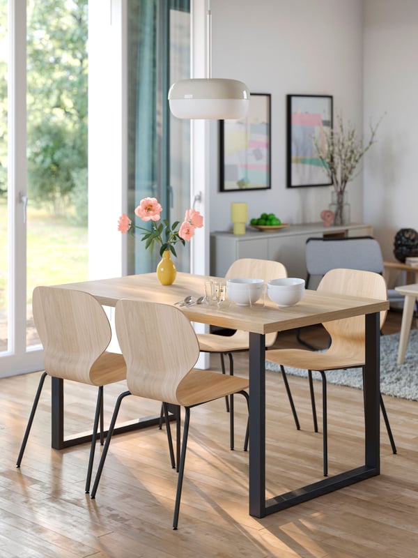 Une table SKÅLSTA en forme de U, en métal tubulaire noir-gris avec placage chêne, et 4 chaises de la même couleur, dans la salle à manger