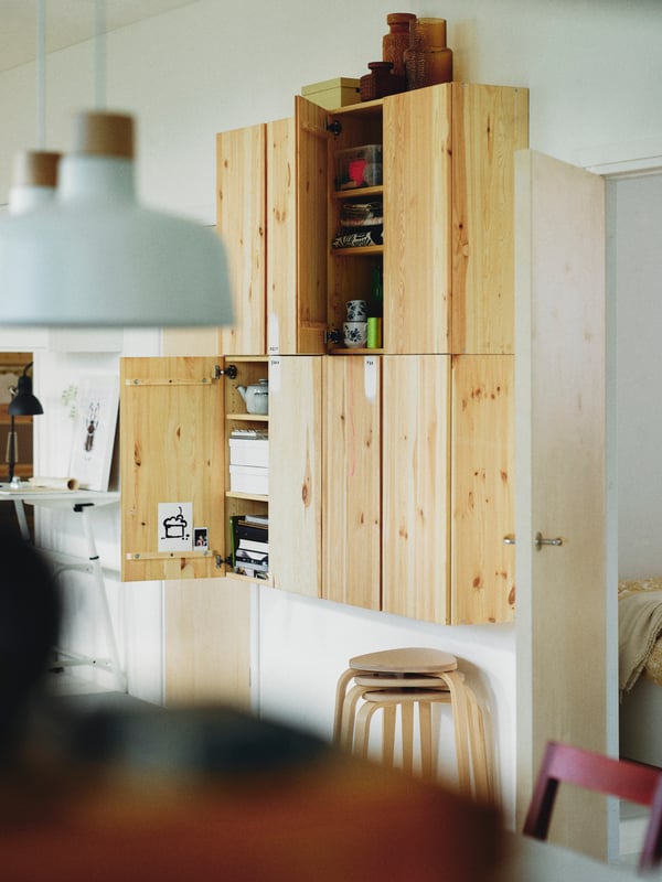 Three stacked birch KYRRE stools below four pine IVAR cabinets attached to a wall.