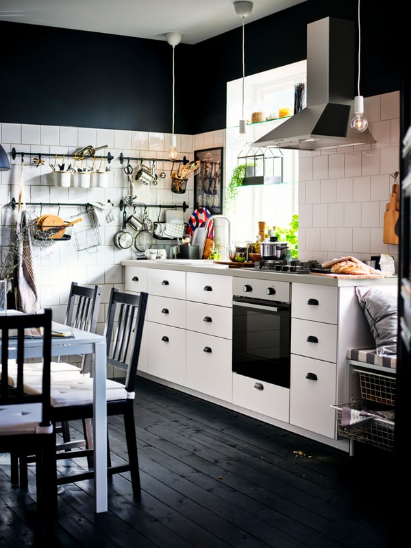 A kitchen with a dark wood floor, white METOD cabinets with MAXIMERA interiors, a GÖRLIG oven and a LUFTIG extractor hood.