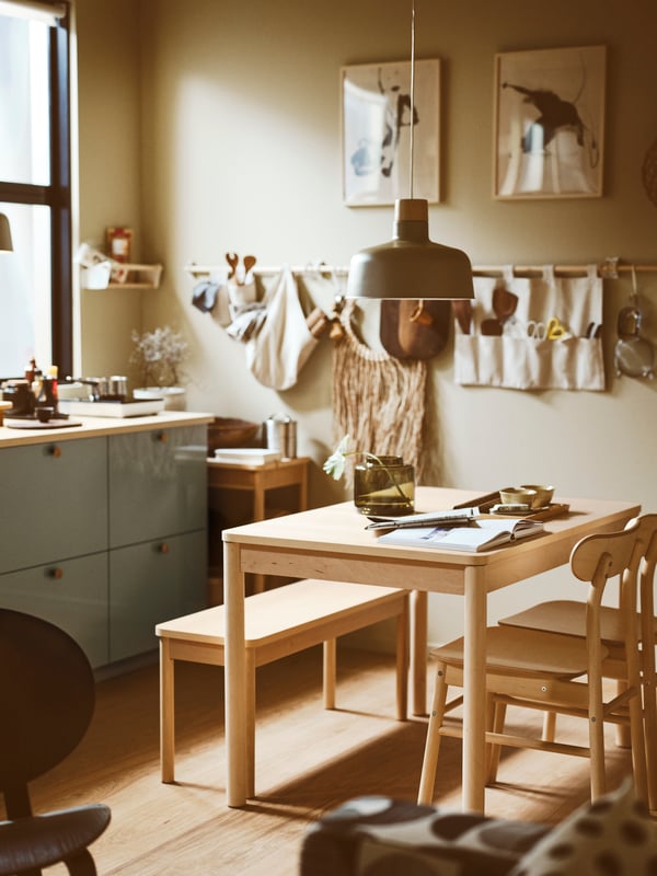A kitchen with a birch RÖNNINGE extendable table, two birch RÖNNINGE chairs and a bench, below a pendant lamp.