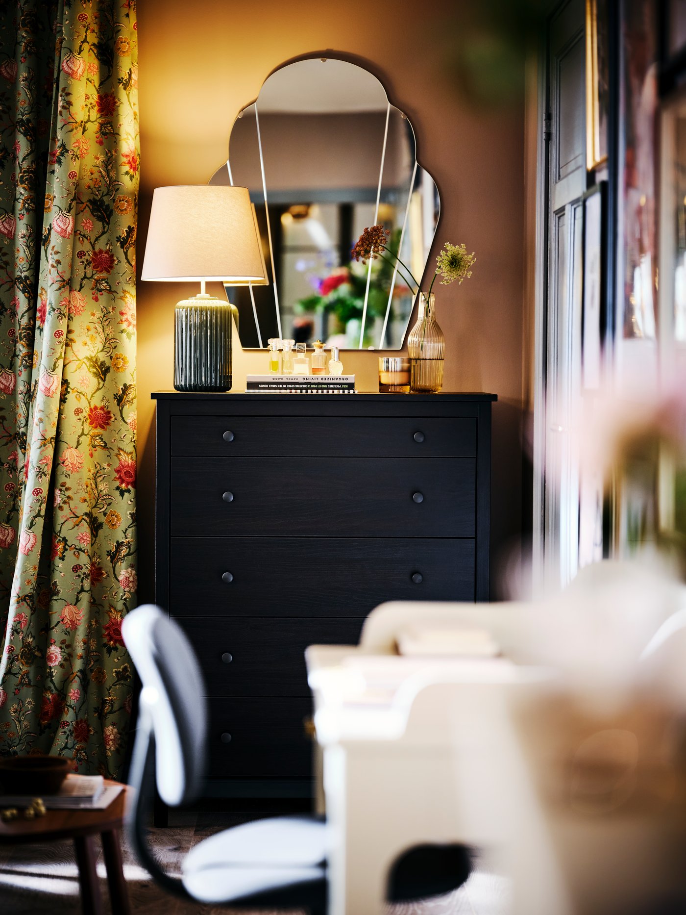 A KOPPANG chest of drawers, with a lit SNÖBYAR table lamp, against a wall with a LOMMARYD mirror.
