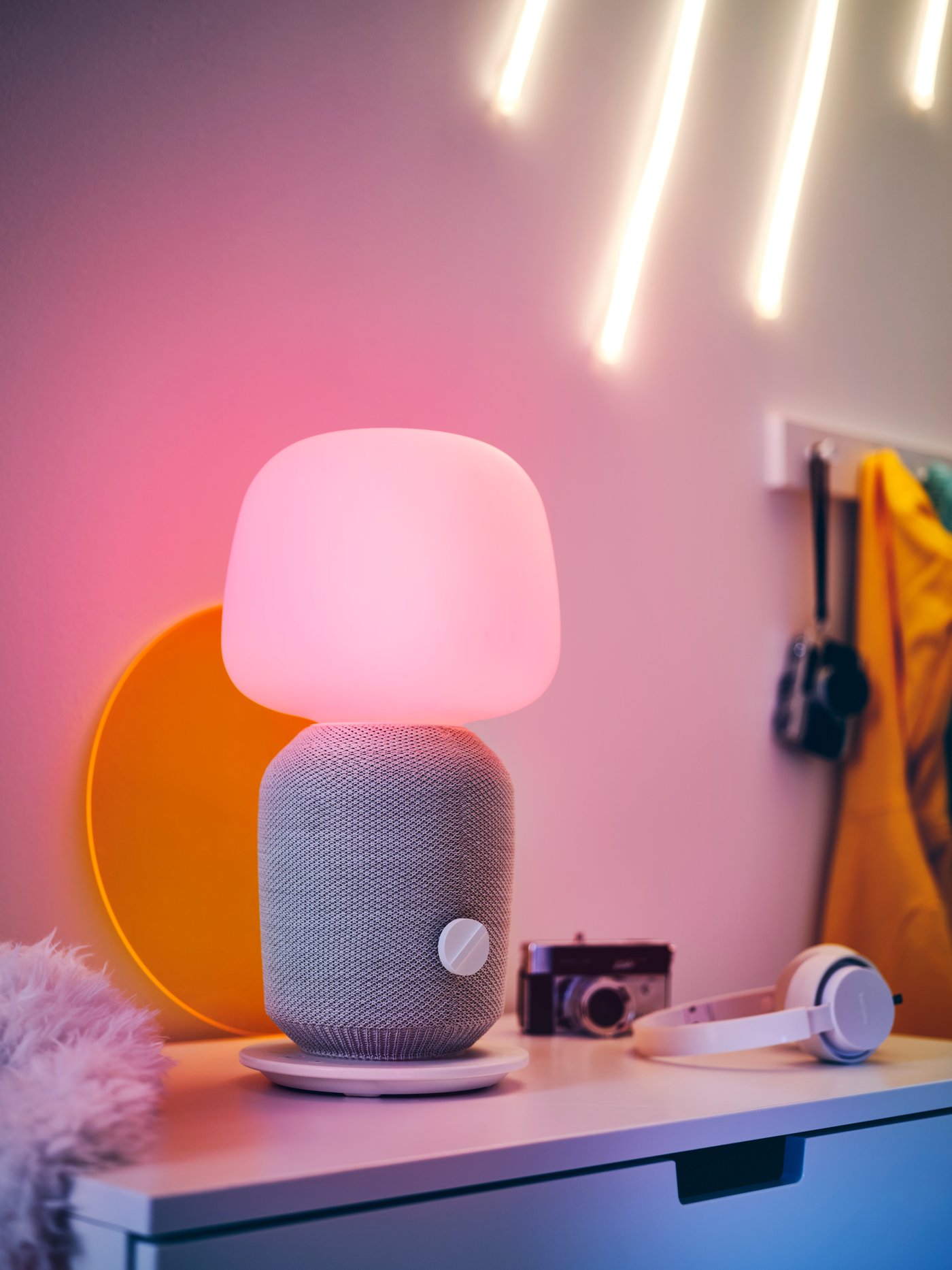 Una lámpara de altavoz SYMFONISK en un escritorio con auriculares al lado.