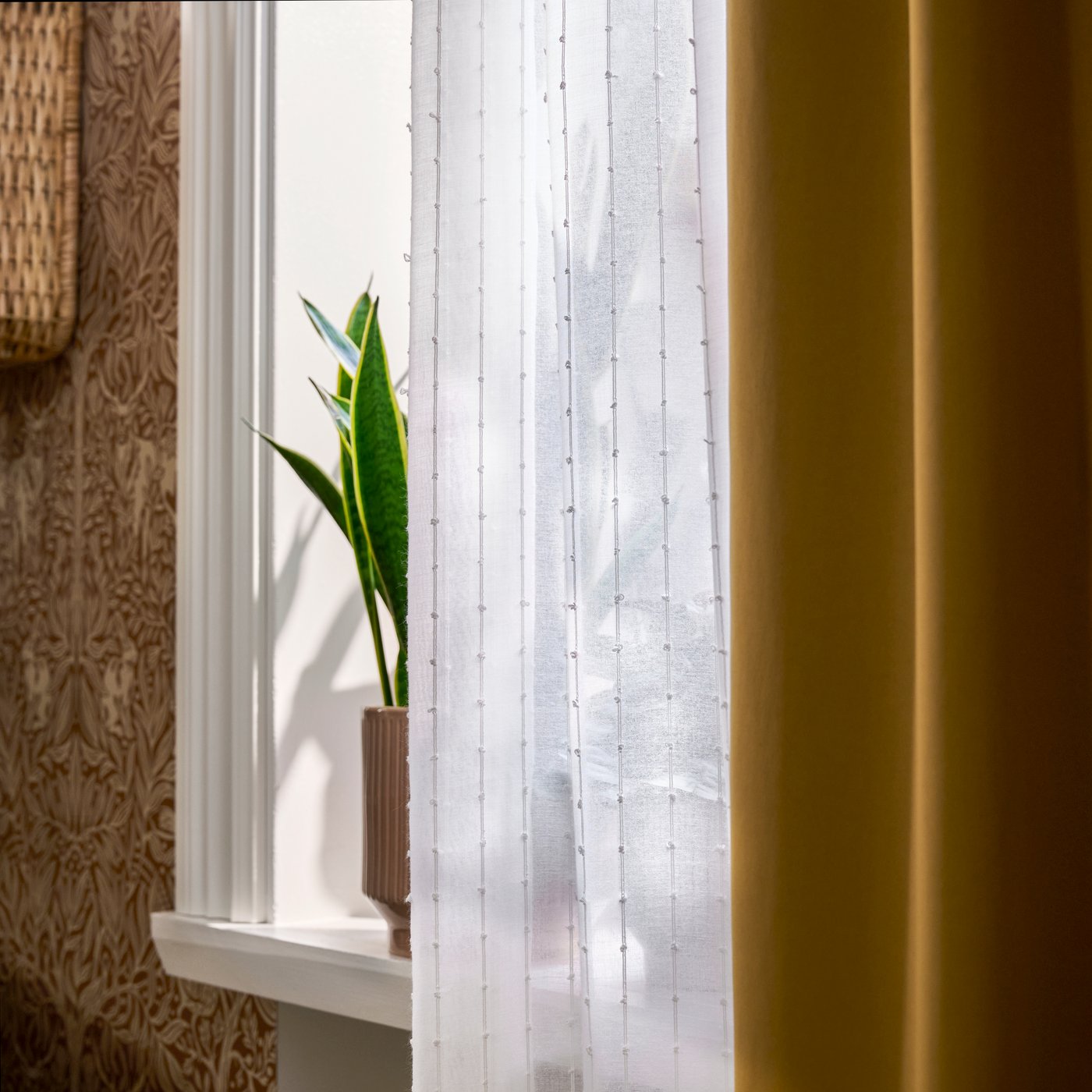 MATILDA transparenter Vorhang in Weiß hängt am Fenster, Sonnenlicht fällt neben gelbem Vorhang und Pflanze hindurch.