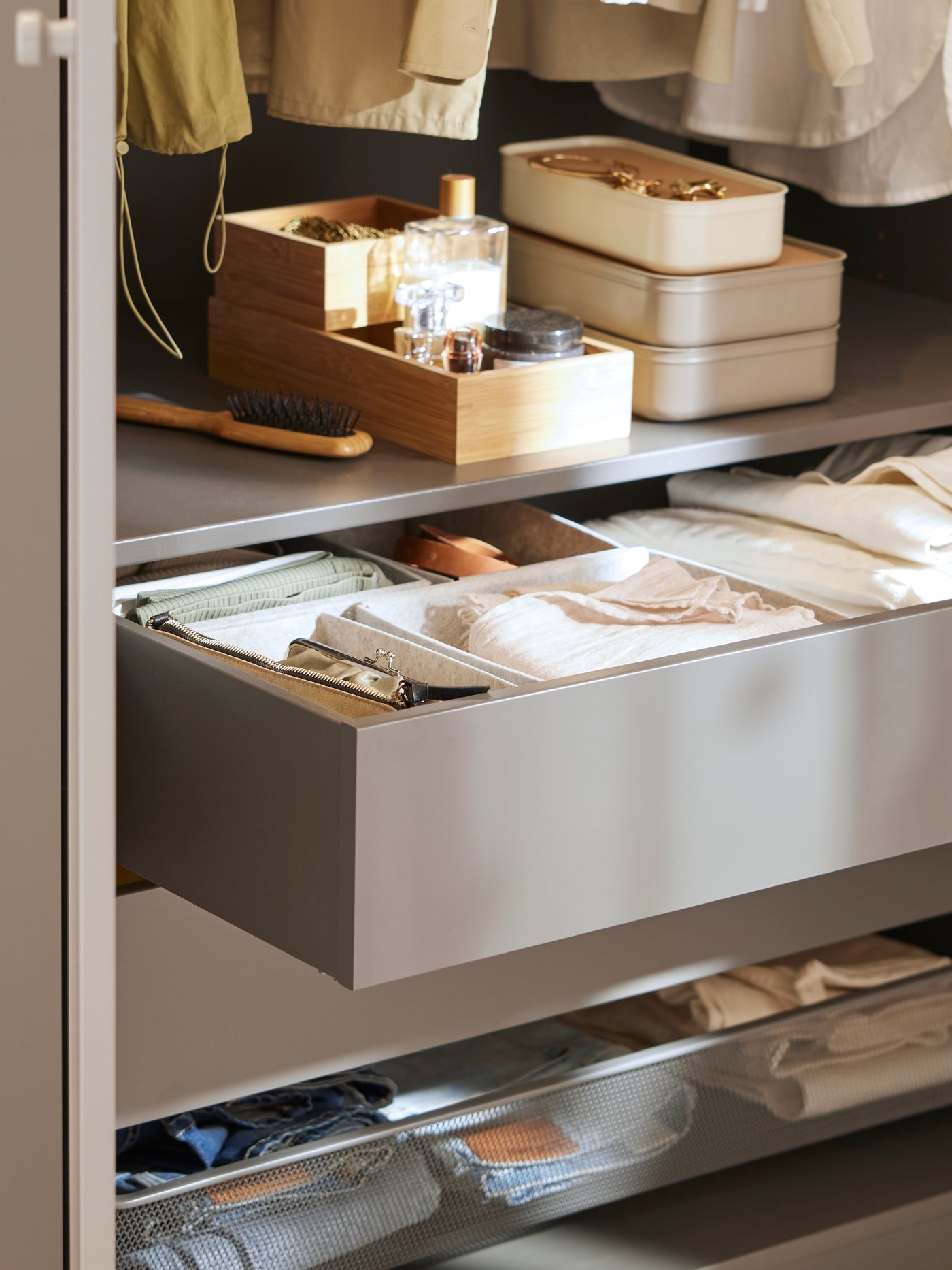 An open drawer in a dark grey/grey PAX/GULLABERG wardrobe showing different KOMPLEMENT boxes inside holding accessories.