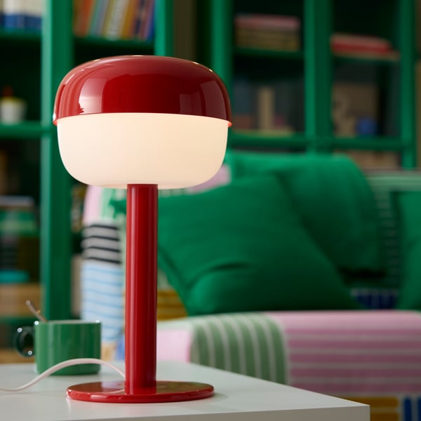 Retro style red and white table lamp in green living room setting.