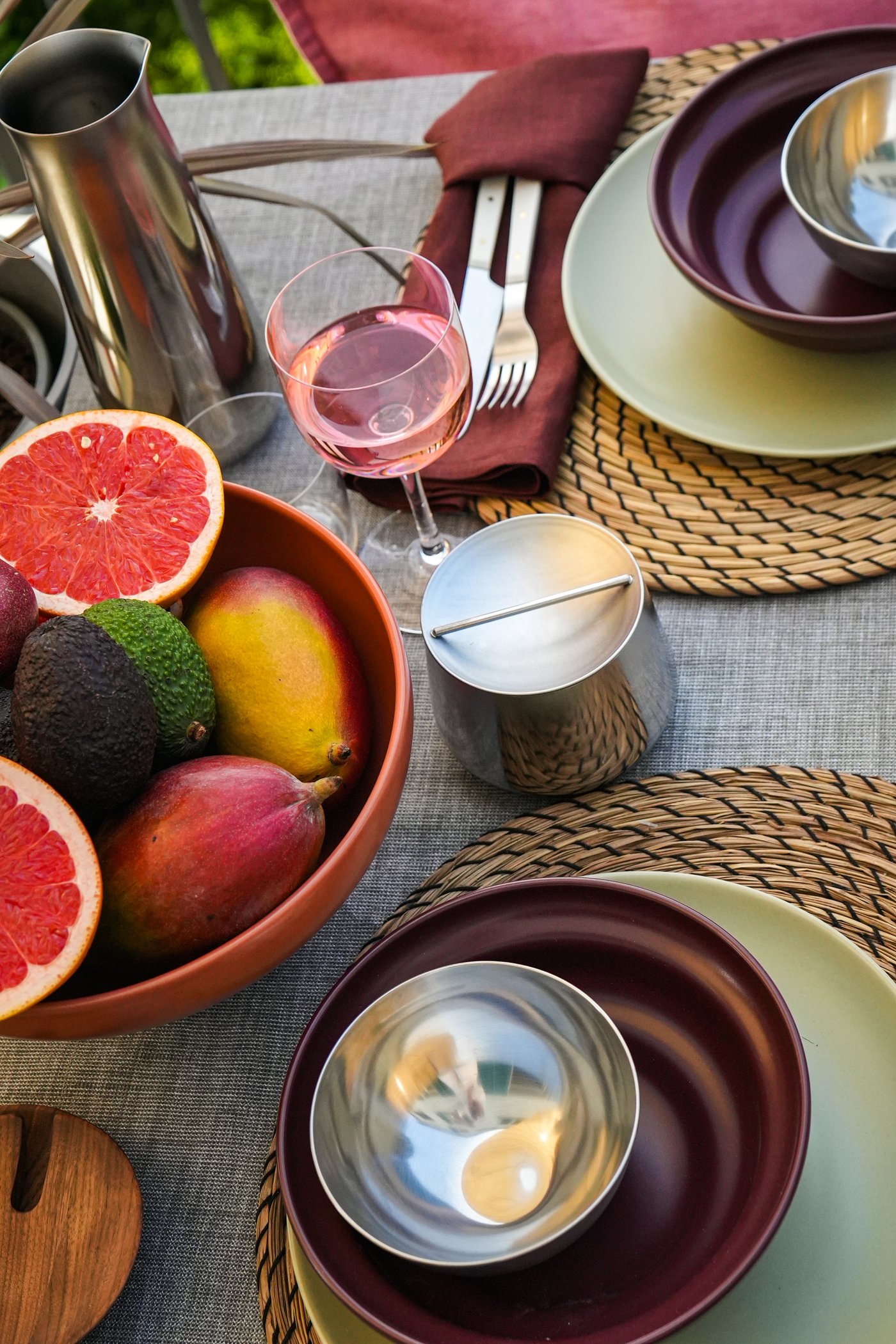 Tischdekoration mit einer BLOMVECKLARE Fruchtschale, Grapefruits, Roséwein, Besteck in violetter Serviette, Tellern und silbernem Geschirr für ein stilvolles Essen.