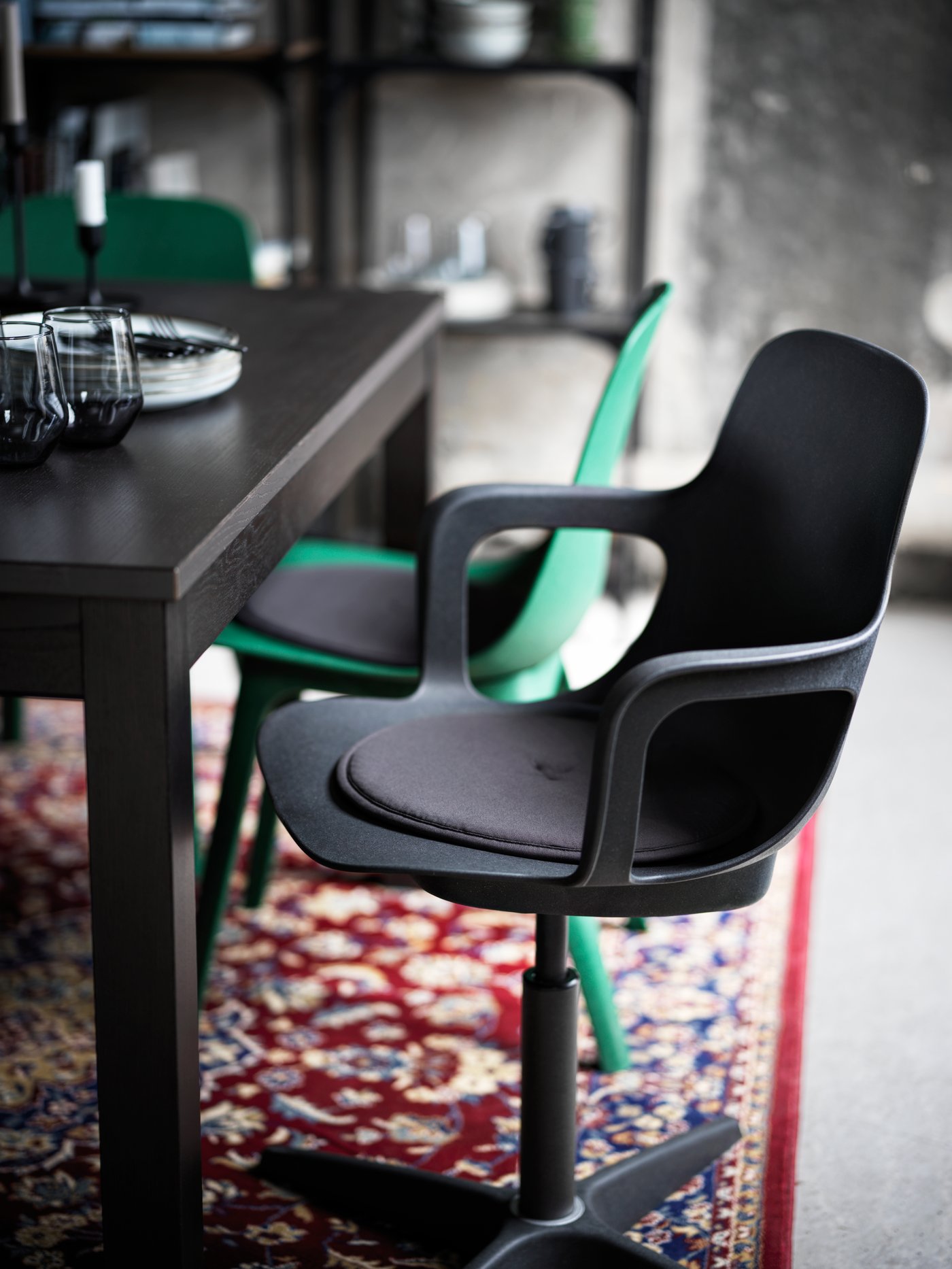 A section of a dining area with an anthracite ODGER swivel chair and a brown LANEBERG table standing on a VEDBÄK rug.