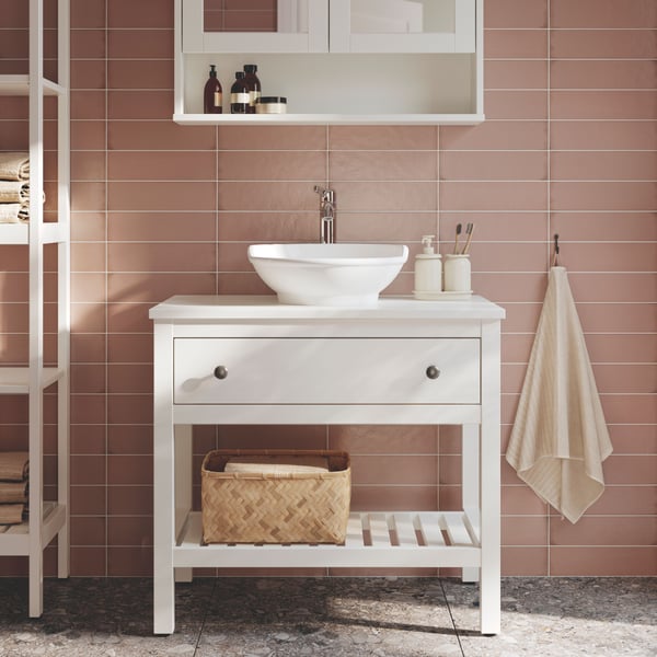 حامل حوض HEMNES أبيض مفتوح بدرج واحد به حوض غسيل مسطح VÄSTERSÖN وخزانة HEMNES بيضاء بمرآة.