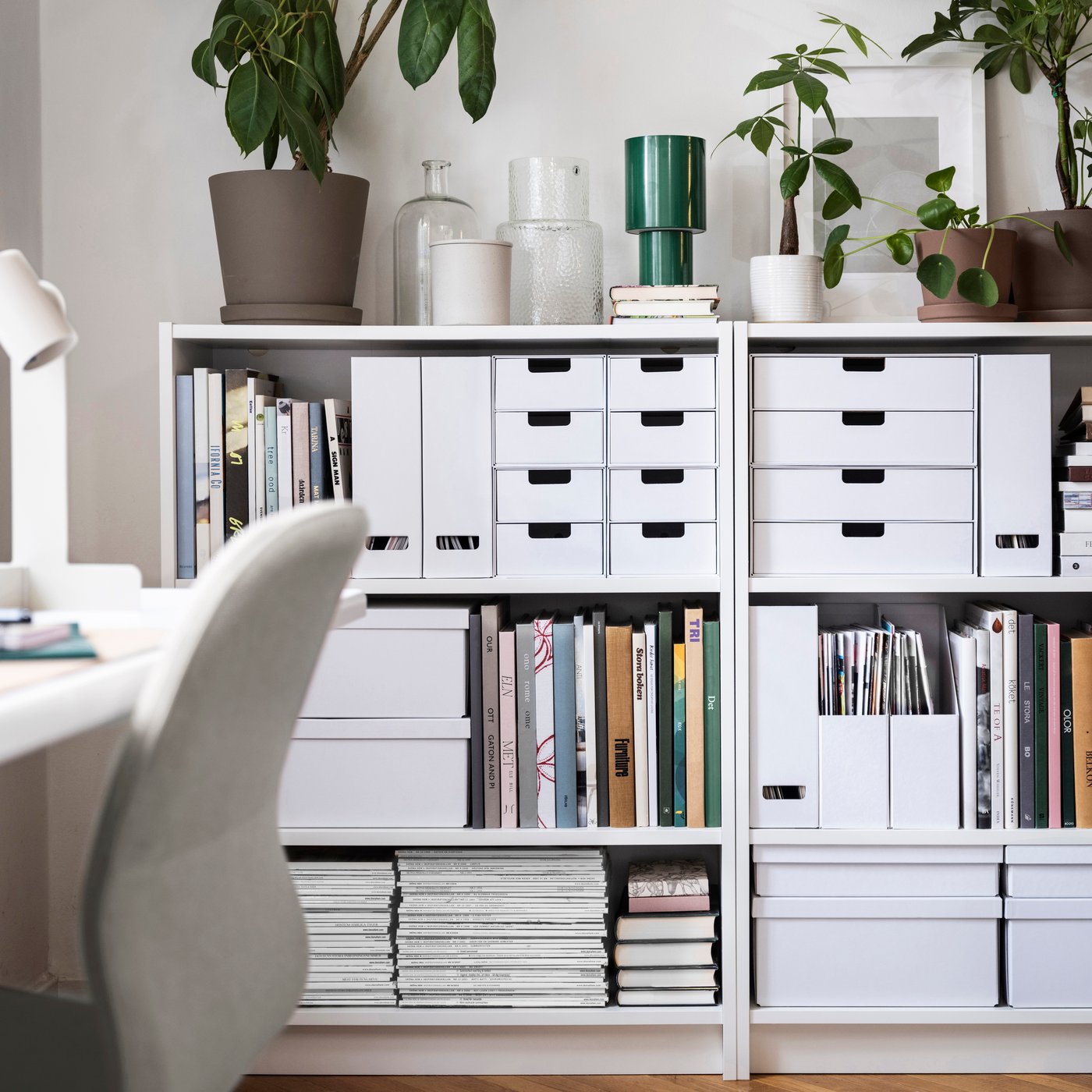 White FJÄDERHARV storage boxes with lid, magazine files and mini chests with 2 drawers stand in bookcases against a wall.