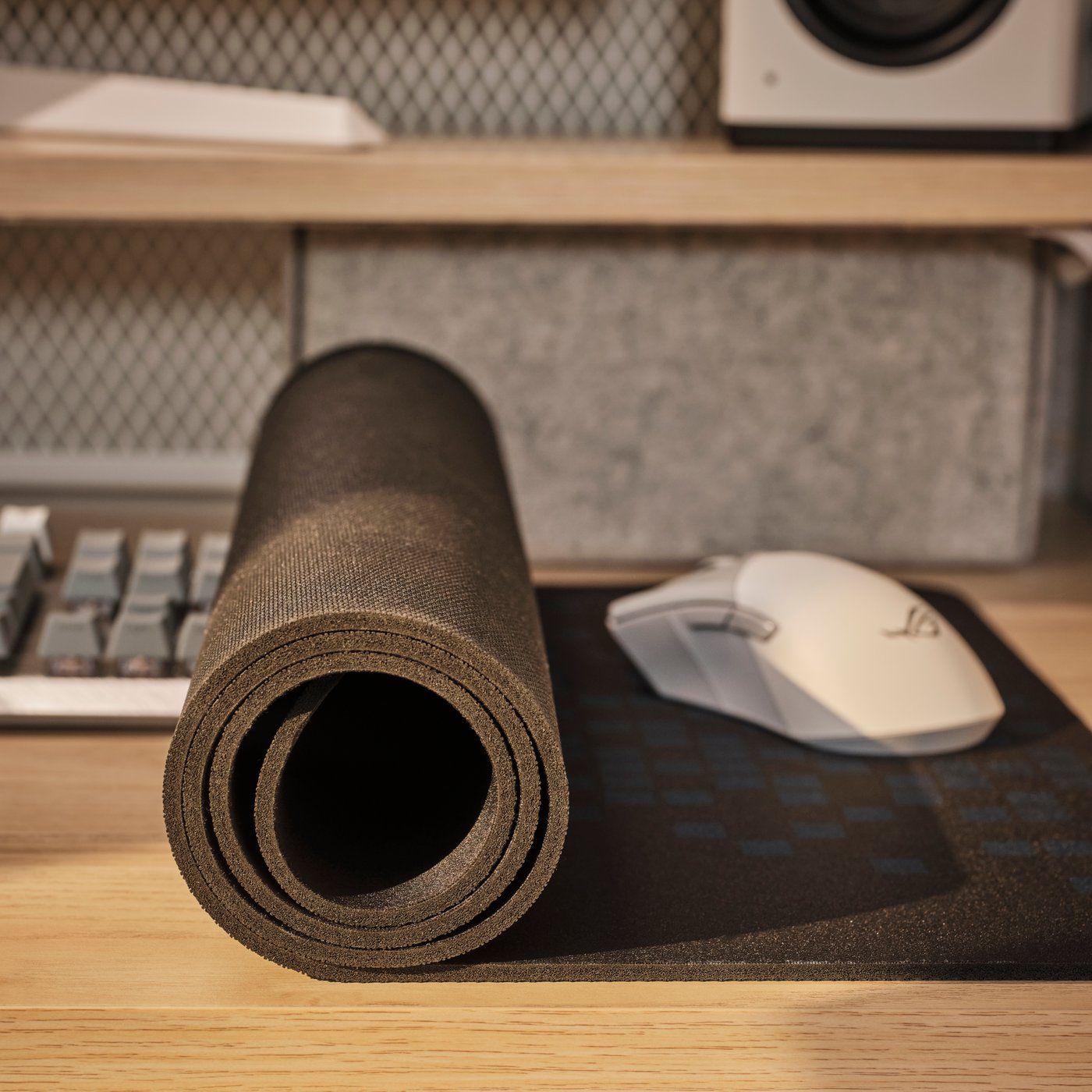 Auf einem Schreibtisch ist ein teilweise aufgerolltes BRÄNNBOLL Gaming-Mousepad zu sehen. Auf dem ausgerollten Teil befindet sich eine Mouse.