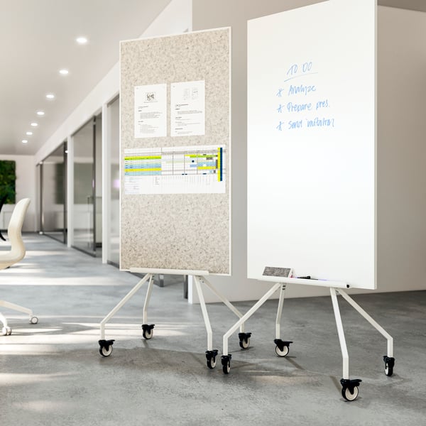 Two ELLOVEN whiteboards/noticeboards on wheels next to each other in an airy office. Double-sided, for notes and for writing.
