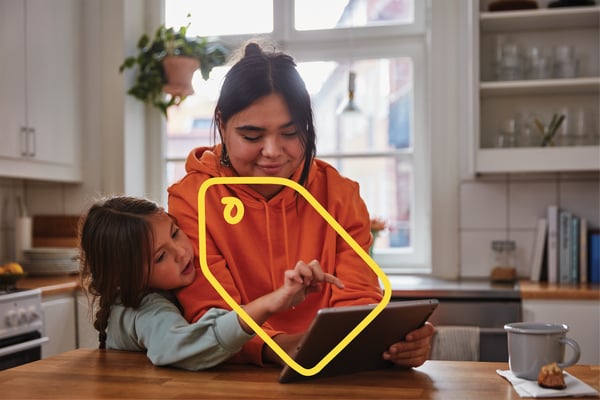 A woman and child are looking at a phone while sitting at the table