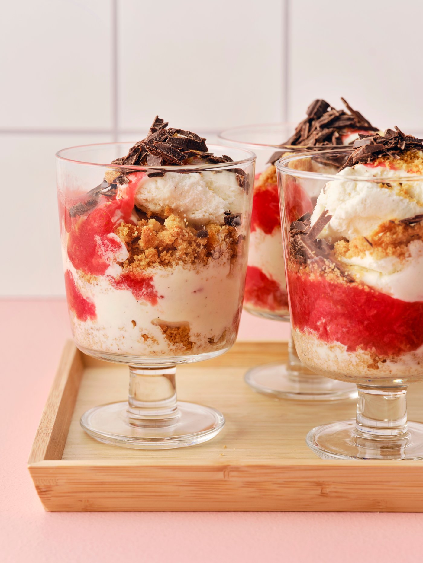 Ice cream with strawberry sauce & chocolate on a bamboo tray.