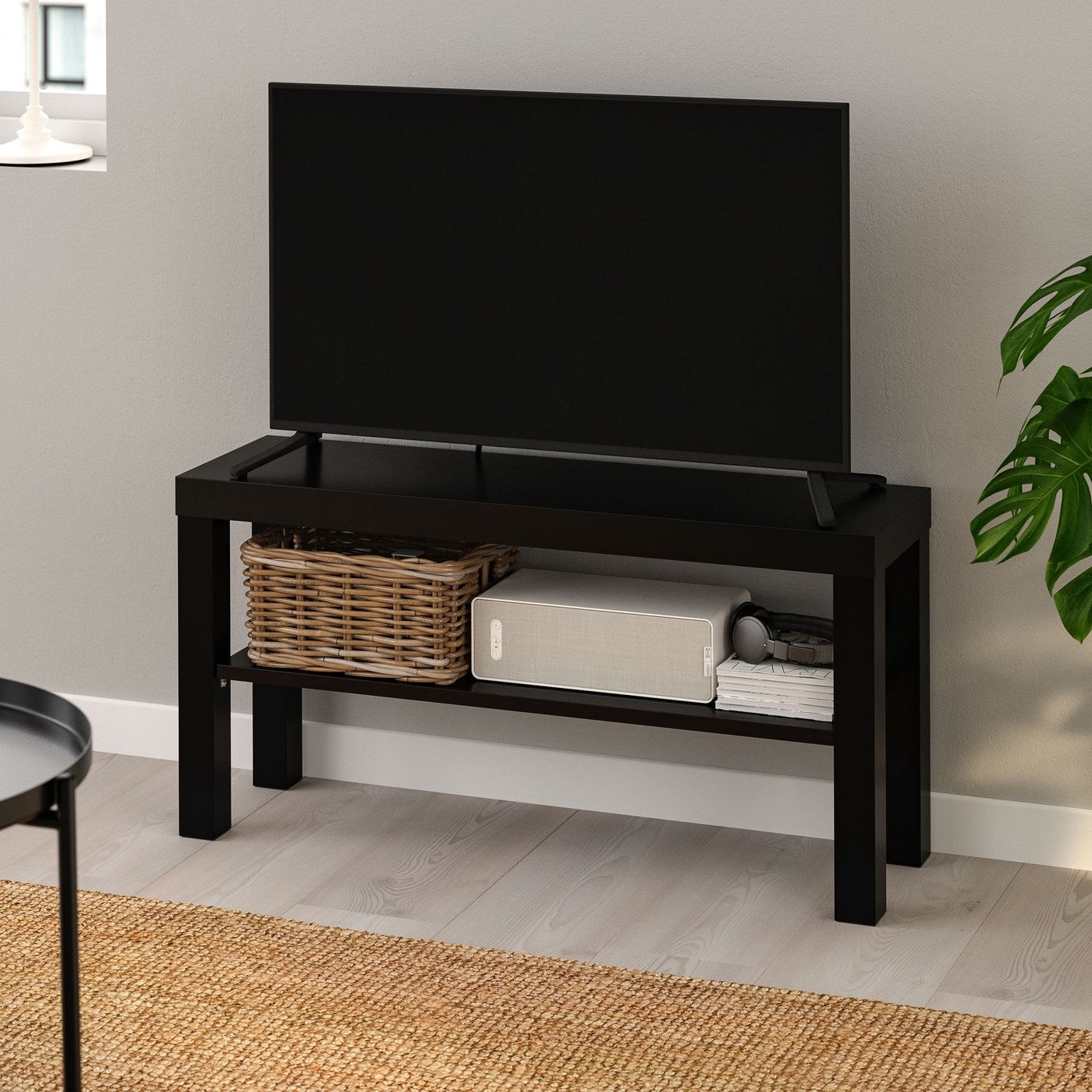Liten enkel tv-bänk i svart med hylla.